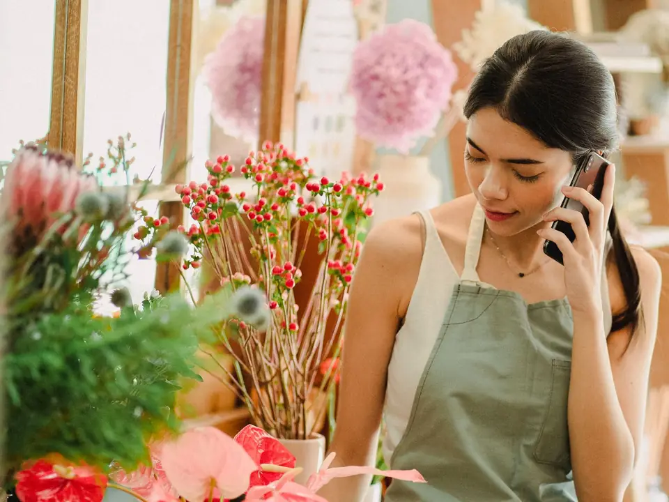 A florist on a phone call in her flower shop