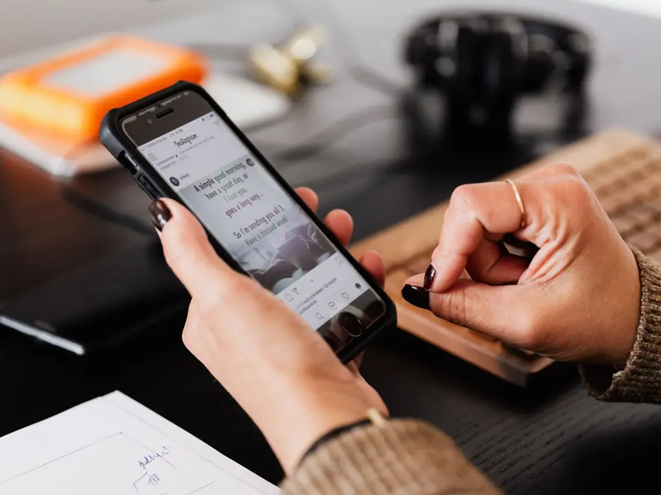 Hands holding a smartphone above paperwork on a desk